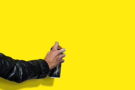 hand with a balloon for graffiti against a pure yellow of the wall. Photo copy space.の写真素材