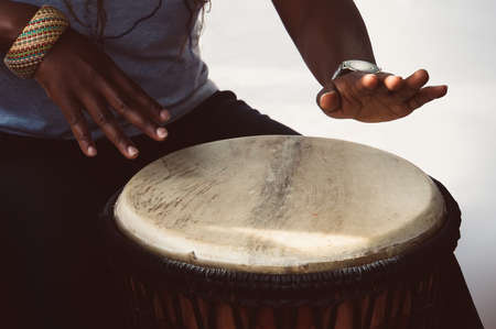 A female african musician plays the djembe drum. She is against a white background.の写真素材