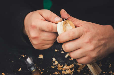 Woodcarving. Manufacturer of wooden kitchen cutting spoon. An old Russian Slavic craft.. hands men...