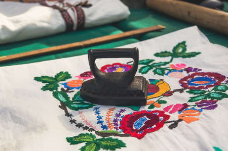 Small baby antique irons for Ironing. Cast iron retro Old iron on white fabric with embroidery....
