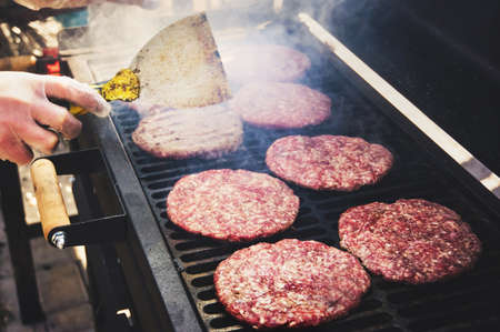 Frozen burger in the cook hand ready for preparing. Round patties of raw minced meat roasted on a metal grid.の写真素材