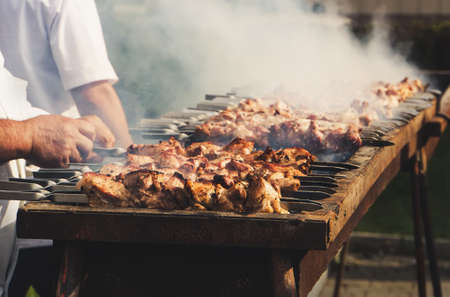 Appetizing delicious fried pieces of meat on skewers are roasted on a large grill in the open air. The chef prepares a barbecue. Shish kebab national cuisine of Central Asia and the middle Eastの写真素材