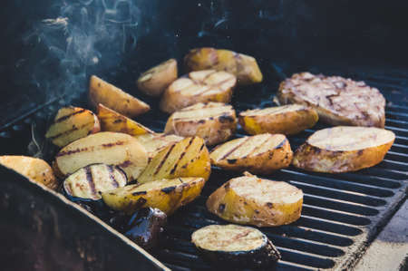 Assorted meat alternative patties, vegetables, tofu and potatoes on cookout grill. beef steak with vegetarian garnishの写真素材