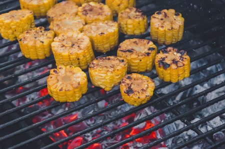 roasted sweet corns on the grill. Burning red coals in the grill. The process of cooking vegetables on burning coalsの写真素材