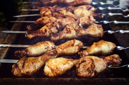 Grilled turkey shin during cooking. Chicken spit-roasted outdoors. Closeup view.