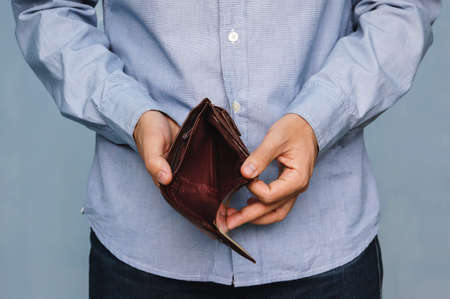 Bankruptcy - Business Person holding an empty wallet. Man showing empty wallet by showing the inconsistency and lack of money and not able to pay the loan and the mortgage.の写真素材