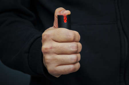 Hand with bottle of pepper spray. protection from criminals. gas cartridge, gas canister