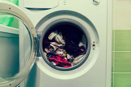 A close up of a washing machine loaded with clothes isolated on white background. The Laundry in the washing machine with the door open.の写真素材