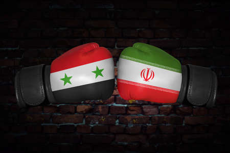 A boxing match. Confrontation between the Iran and Syria. Syrian and Iranan national flags on Boxing gloves. Sports competition between the two countries. Concept of the foreign policy conflict.の写真素材