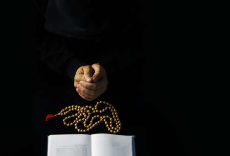 Hands of young priest with holy bible and wood sandalwood rosaryの写真素材