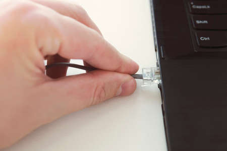 ethernet cable plug connector on computer laptop keyboard technology concept. Hand hold network...