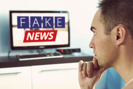 Truth misrepresented in the news on a modern TV. A fake news report. Zombie TV. Deception of viewers. Corrupt journalism. False sites. Agitation and propaganda on the screen. in front of the TV.の写真素材