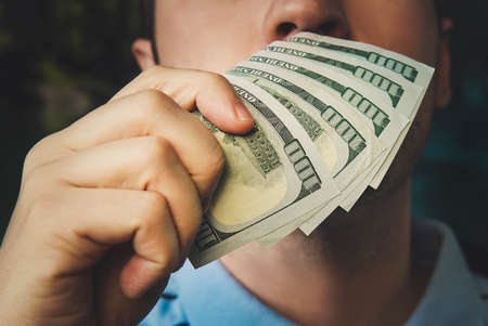 Handsome young businessman holding and smelling money. the smell of money. 500 dollarsの写真素材