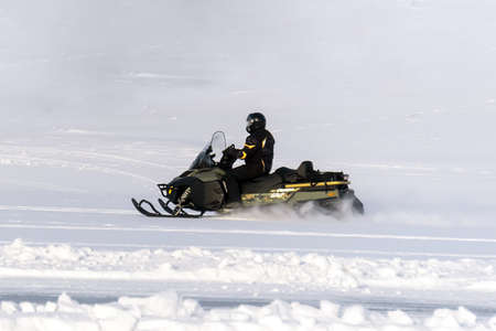 Man driving sports snowmobile in Finnish Lapland in a sunny dayの写真素材