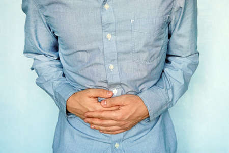 Businessman holding his stomach in pain. heaviness in the stomach after eating. diseases of the gastrointestinal tract. gases in the stomach. stomach irritation. Problems with the digestive processの写真素材
