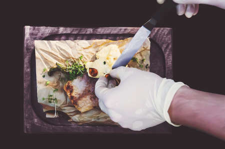 Process of cooking fish. hands cooks in clean white gloves puts a sauce on grilled fish. The view from the top.の写真素材