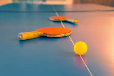 sports competitions in table tennis. two old orange tennis rackets and a yellow ballの写真素材