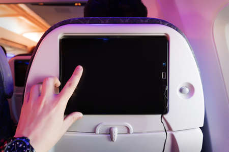 Aircraft monitor the passenger seat. Interior plane. Touch screen. male finger taps on the screen. blank form for design. empty screen. entertainment during the flightの写真素材