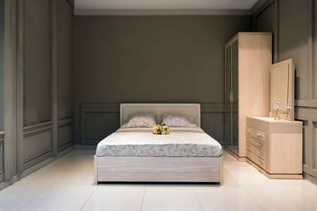 Spacious bedroom in grey, with handmade, wood furniture, big bed and decorative, pattern pillowsの写真素材