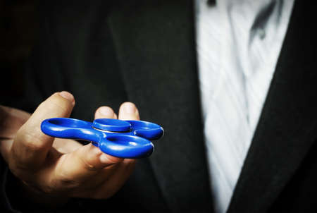 A man holding a blue spinner. Antistress toy to relieve tension at work in the office.の写真素材