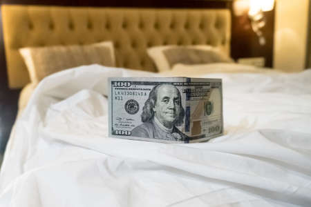 bed and money to symbolize the cost of sex. Paid love the prostitute. Payment for the services of prostitutes. A tip for the staff. buck 100 on the bed. monetary gratitudeの写真素材