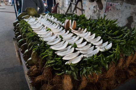 A coconut cut into portions lie on the counter of a street vendor. Night time. The street food. Pile of coconut for sale in marketの写真素材
