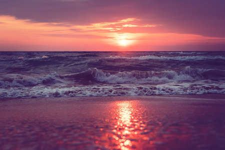 a beautiful sunrise on Sanibel Island Florida. Bright intense pink purple orange sunrise at the sea. Waves at dawn. reflection of sunlight in water and sand on the beach. Tide at dawn. Dramatic viewの写真素材