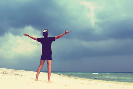 Feel good and freedom concept. Copy space of happy man raise hands on beach background. Vintage tone filter color style.の写真素材