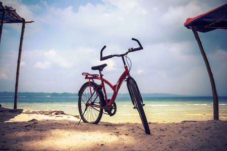 Red bicycle parked in the beach. Bicycle parking in the beach sand. The concept of Cycling. Bike on...