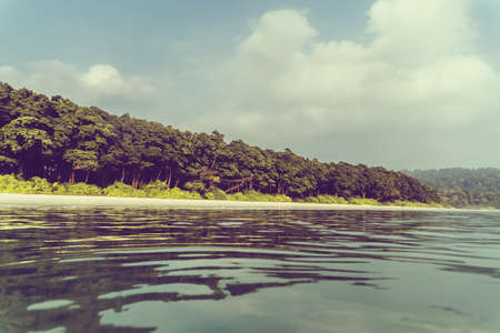 Summer exotic sandy beach with blur palms and sea on backgroundの写真素材