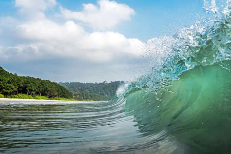 a big wave covers. Radhanagar Beach At Andaman and Nicobar Island, India. view from the sea. bursts of water at sea. The spray of water droplets. under the crest of a wave. crest of waveの写真素材