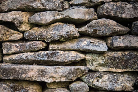 background of old stones in the wall. the texture of the stone covered with mossの写真素材