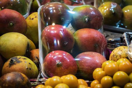 Concept street trade exotic fruits. Tropical fruits on counter of a street shop. Ripe yellow mango and dragon fruit. Night trade in Asia.の写真素材