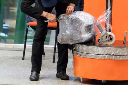 Luggage wrapping service at the airport terminal for security reason and safety protection from damage. Wrapping baggage before travel by airplane.の写真素材