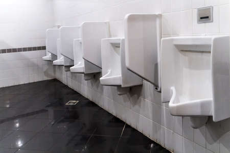 Closeup white urinals in men's bathroom, design of white ceramic urinals for men in toilet room....