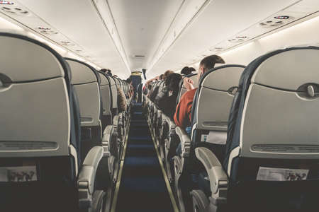 Interior of airplane with passengers on seats waiting to taik off. Horizontal composition. boring flight in economy class aircraft salon. economy classの写真素材