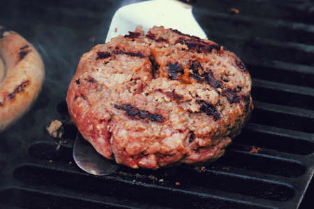 Turkish home made meatball ready to be grilled. big fried meat Patty on the grill. the cook turns the meat on the grill. The process of making the toppings for a Burgerの写真素材