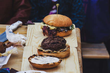 Burger hamburger on a dark background with fresh vegetables. Preparing sandwiches at home on the kitchen table. The Patty bun on a wooden Board.の写真素材