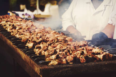 Grilled kebab cooking on metal skewer. Roasted meat cooked at barbecue. BBQ fresh beef meat chop slices. Traditional eastern dish, shish kebab. Grill on charcoal and flame, picnic, street foodの写真素材