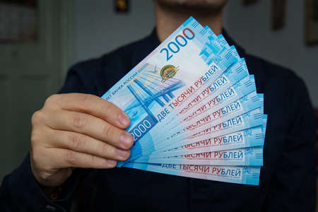 new Russian banknotes denominated in 2000 rubles in male hands close-up on a dark backgroundの写真素材