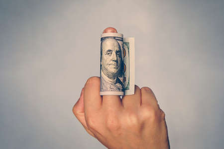 Man shows middle finger with dollar bill on it. Concept of bribe, dishonesty, hypocrisy.の写真素材
