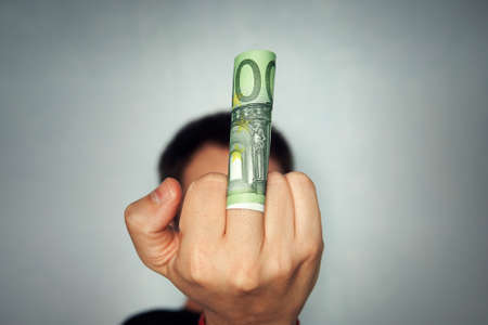Rude male giving money and showing middle finger.の写真素材