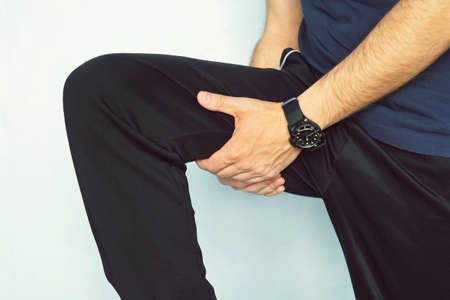 Muscle injury. Man with sprain thigh muscles. Athlete in sports shorts clutching his thigh muscles after pulling or straining them while joggingの写真素材