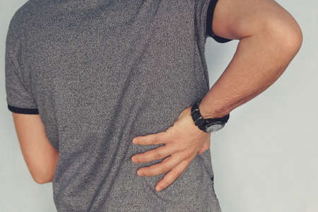 close up of a man holding his back in pain.の写真素材