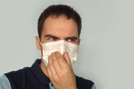 young father holding dirty dirty diaper in one hand fingers with gas mask over white background.の写真素材