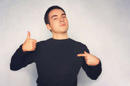 Attractive young man in white t-shirt pointing right with his finger on blue background.の写真素材