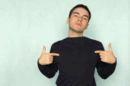 man pointing at his t-shirt can be used as a clothes design template on a blue background.の写真素材
