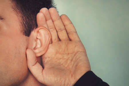 Listening male holds his hand near his ear. concept of deafness or eavesdropping. Hard of hearing.の写真素材