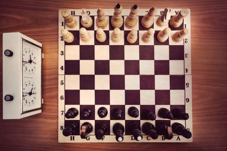 Chessboard with chess and clock, top view. The beginning of the chess game. the first moveの写真素材