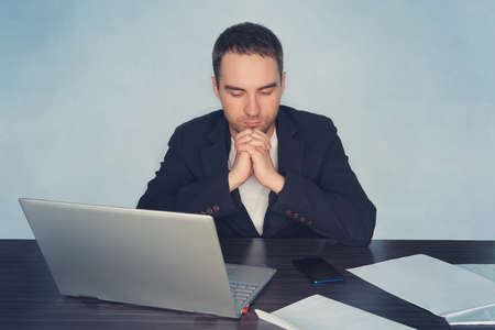 business, overwork, people, deadline and technology concept - stressed businessman with laptop computer thinking at office. a man prays for his business.の写真素材